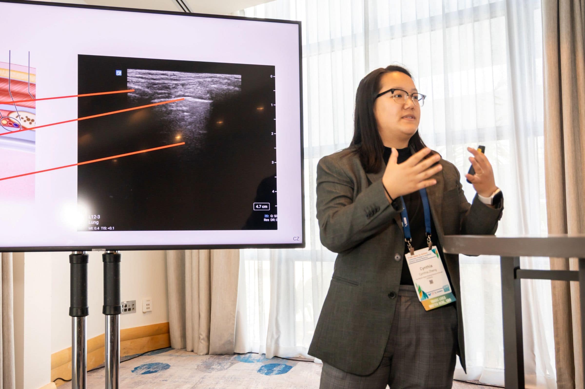 1P4A2558v2 Person speaking at podium, in front of a clinical image on the screen behind them