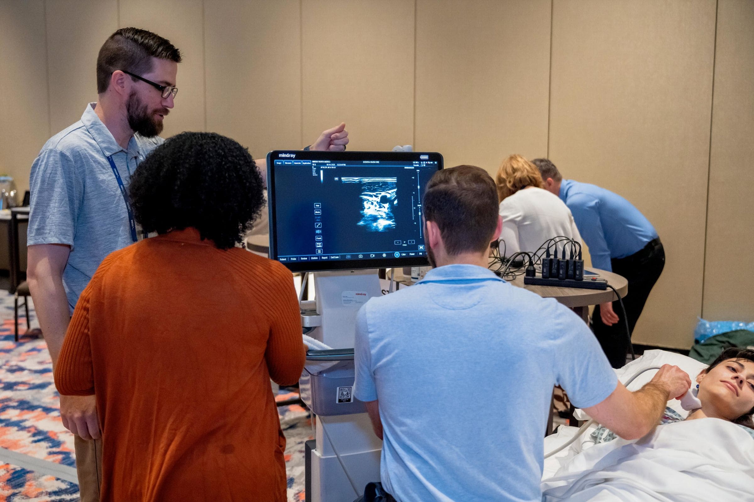 _AC76870v2 A group of people gathered around a demonstration table at a ultrasound training workshop