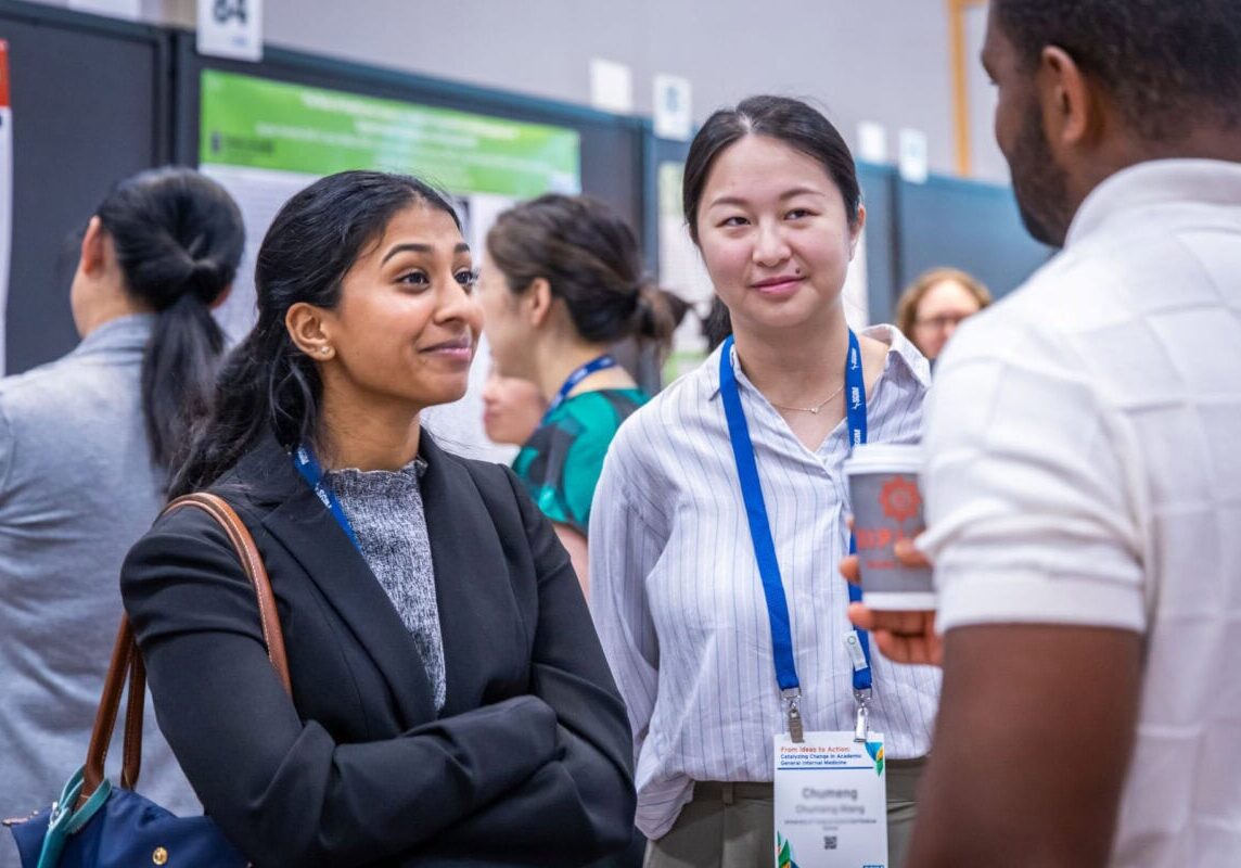 Three smiling conference attendees talking to one another