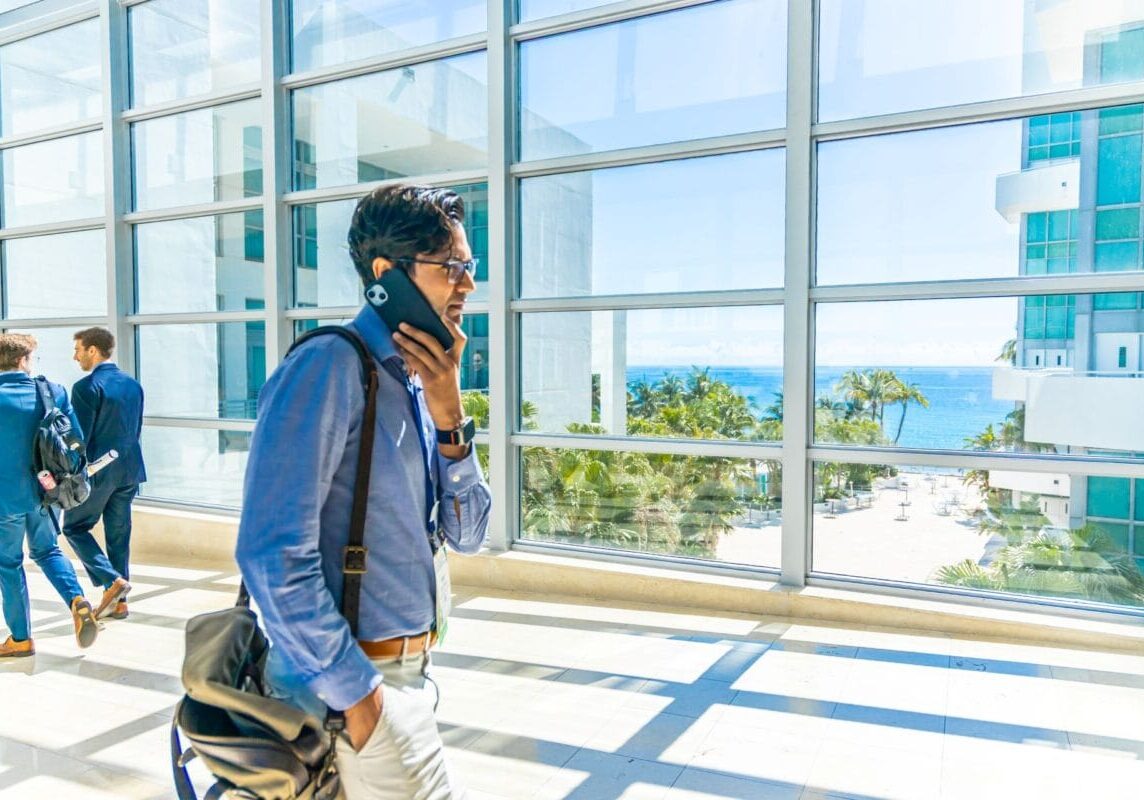 a person, holding a phone, walks through a sunny walkway