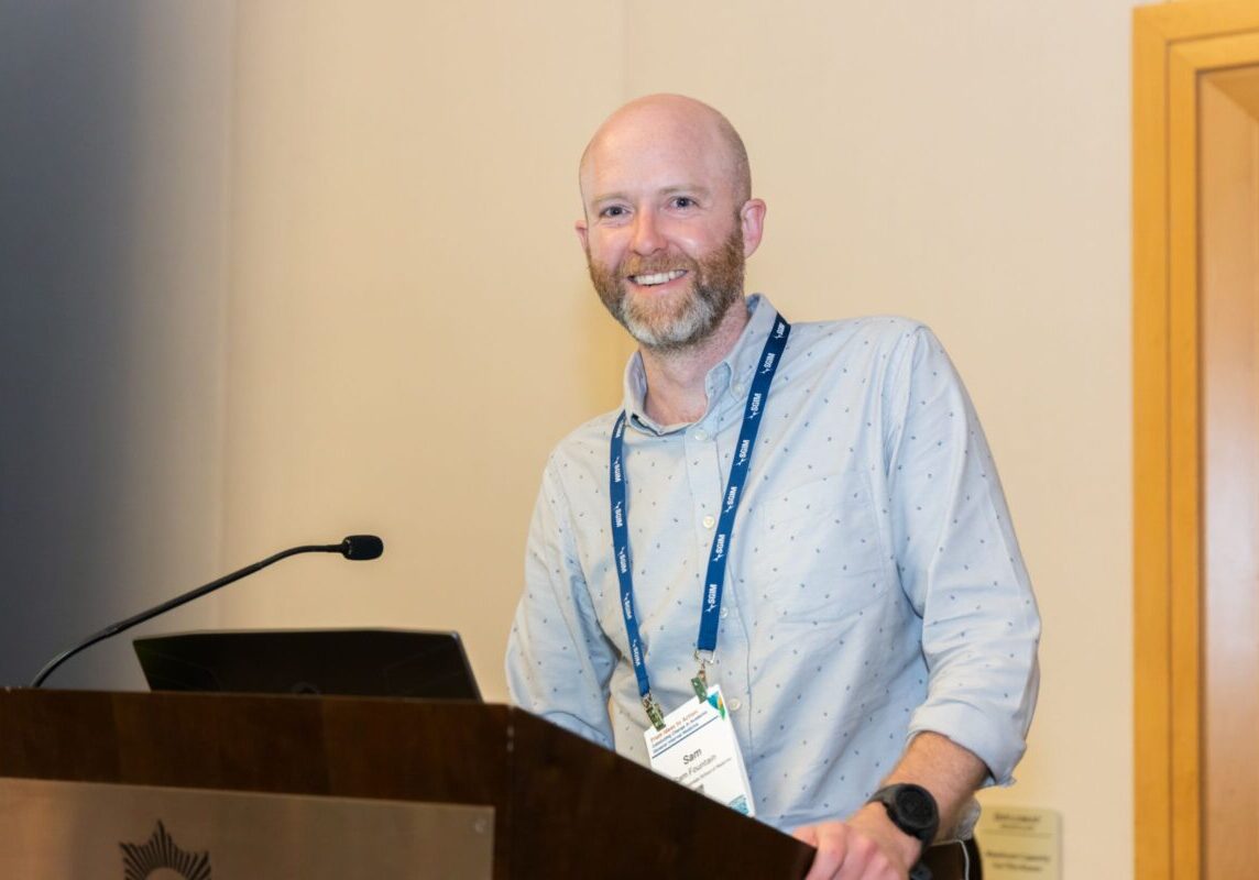Conference speaker, smiling at the podium