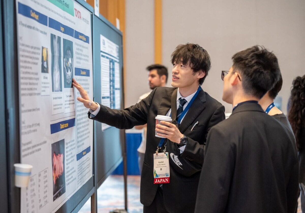 A conference attendee is presenting a poster to another attendee